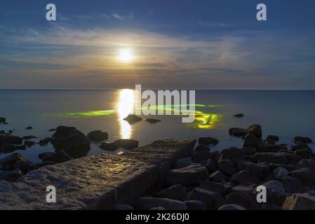 Una luna piena sul mare di notte e subacquei con lanterne in acqua. Foto Stock
