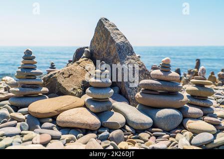 Piramidi di pietra disposte sulla riva del mare. Foto Stock
