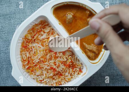 pollo al curry e riso in una confezione di plastica da portare via sul tavolo Foto Stock