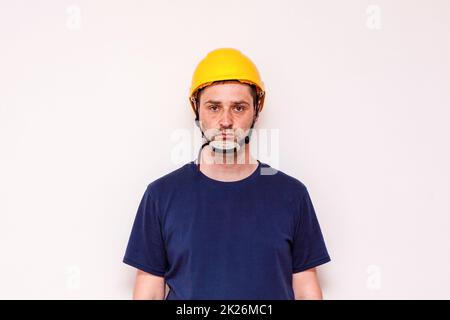 Lavoratore di costruzione dietro sfondo bianco. Indossare maschera verde e casco giallo Foto Stock