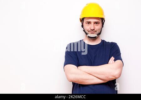 Lavoratore di costruzione dietro sfondo bianco. Indossare maschera verde e casco giallo Foto Stock