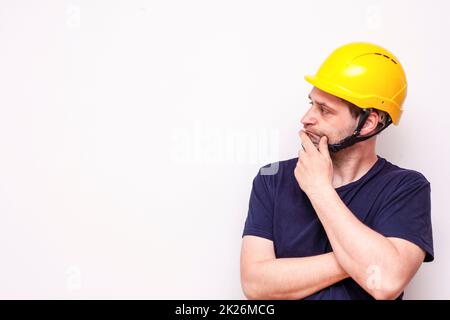 Lavoratore di costruzione dietro sfondo bianco. Indossare maschera verde e casco giallo Foto Stock