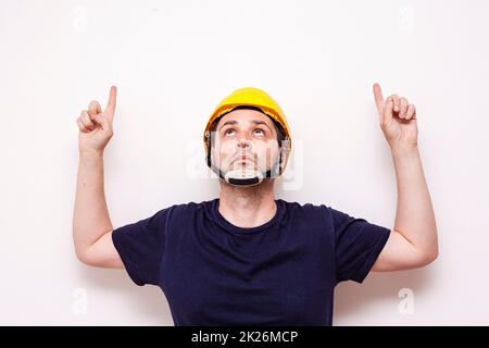 Lavoratore di costruzione dietro sfondo bianco. Indossare maschera verde e casco giallo Foto Stock