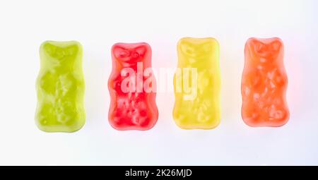 orsacchiotti gommoso di colore verde, rosso, giallo e arancione in fila affiancati su sfondo bianco Foto Stock