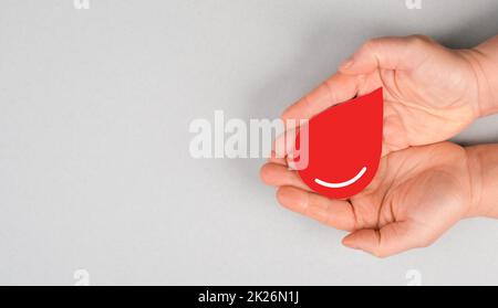 Tenere una goccia rossa nelle mani, donare il sangue, giornata mondiale dei donatori di sangue, assistenza sanitaria, trasfusione Foto Stock