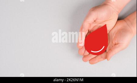 Tenere una goccia rossa nelle mani, donare il sangue, giornata mondiale dei donatori di sangue, assistenza sanitaria, trasfusione Foto Stock