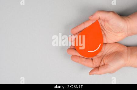 Tenere una goccia rossa nelle mani, donare il sangue, giornata mondiale dei donatori di sangue, assistenza sanitaria, trasfusione Foto Stock