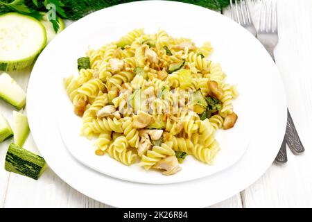 Fusilli con pollo e zucchine in due piatti su lavagna bianca Foto Stock