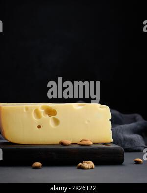 pezzo triangolare di formaggio maasdam su un asse di legno marrone Foto Stock