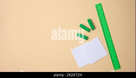 set di oggetti di cancelleria righello, fogli di carta bianca bianca bianca bianca e sfondo beige. Vista dall'alto Foto Stock