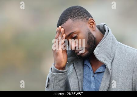 Uomo preoccupato con pelle nera che si lamenta in inverno Foto Stock