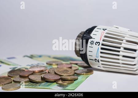 Aumento dei prezzi dell'energia e consumo di energia regolatore termostatico dal riscaldamento con banconote e monete in euro Foto Stock