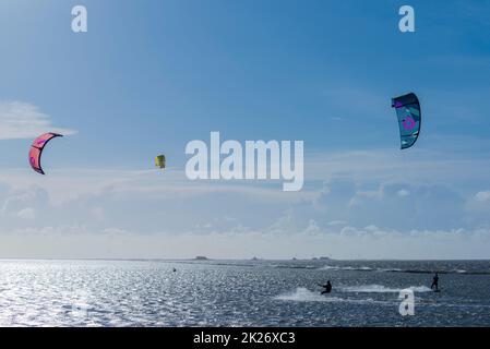 Kitesurf sul Mare del Nord a Lüttmoorsiel, Hallig Nordstrandischmoor all'orizzonte, Nr Frisia, Germania del Nord Foto Stock