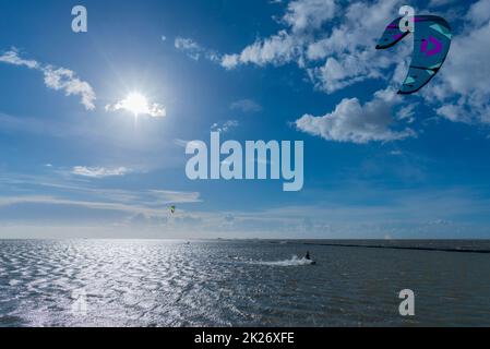 Kitesurf sul Mare del Nord a Lüttmoorsiel, Hallig Nordstrandischmoor all'orizzonte, Nr Frisia, Germania del Nord Foto Stock