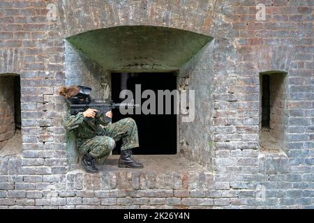 donna in uniforme con una pistola in allenamento militare paintball Foto Stock