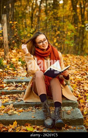 Primo piano di una giovane donna che legge libro all'aperto Foto Stock