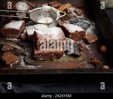 pezzi quadrati di brownie al cioccolato al forno cosparsi di zucchero a velo sul tavolo Foto Stock