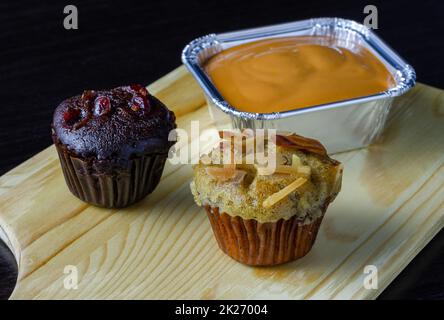 Muffin al cioccolato, cupcake alla banana e torta al fudge al tè del latte su vassoio di legno Foto Stock