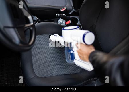 Pulizia degli interni dei sedili per auto con aspirapolvere portatile Foto Stock