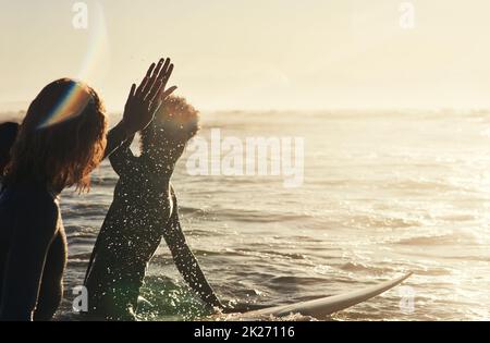 Mantenere l'atmosfera. Shot di un gruppo di giovani surfisti che navigano insieme nell'oceano. Foto Stock