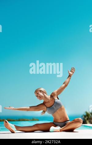 Tenere e respirare. Una giovane donna attraente che si allunga con le braccia distese dopo il suo allenamento in piscina in una giornata di sole. Foto Stock
