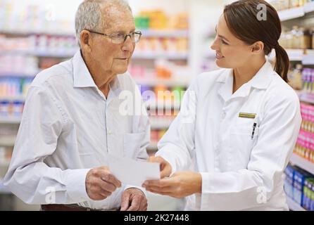 Spiegare le prescrizioni in linguaggio semplice. Shot di un giovane farmacista che aiuta un cliente anziano con la sua prescrizione. Foto Stock