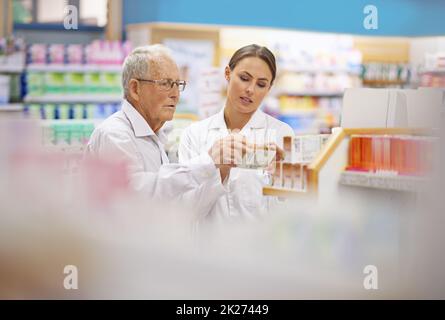 Fornire ai clienti tutti i fatti. Shot di un giovane farmacista che aiuta un cliente anziano. Foto Stock