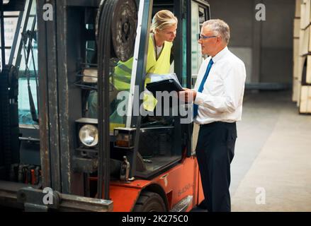 Ascolta e impara dal meglio. Un manager che dà ordini a un dipendente seduto su un carrello elevatore. Foto Stock