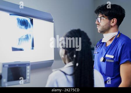 Che succede all'interno del petto. Shot di un gruppo di chirurghi che discutono di un paziente raggi X durante l'intervento chirurgico. Foto Stock