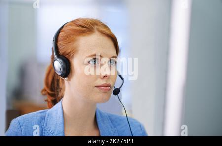 Prendo sul serio tutte le mie domande. Scatto di un'attraente donna con testa rossa seria su una domanda che ha sulla sua cuffia. Foto Stock