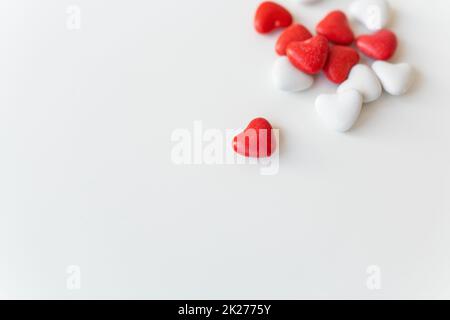 Lo sfondo piatto del giorno di San Valentino si trova sulla parte superiore della vista delle caramelle rosse e bianche a forma di cuore sparse su sfondo bianco. Luogo per un'iscrizione. Foto Stock