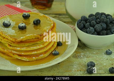 Pancake con mirtilli, sciroppo d'acero su un rustico sfondo bianco Foto Stock