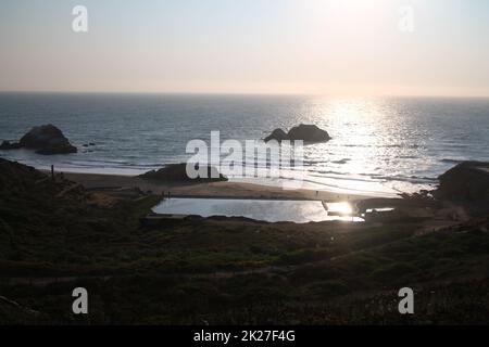 Un tramonto giallo sull'oceano sui bagni Sutro a San Francisco Foto Stock