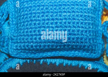 Piccolo cuscino di lana lavorato a maglia primo piano. tessuto di lana blu Foto Stock