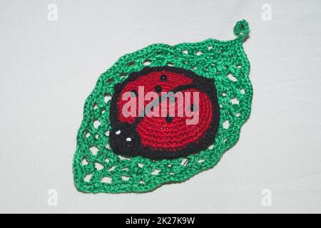 Giocattolo a maglia per coccinelle. primo piano su cuscino fatto a mano Foto Stock