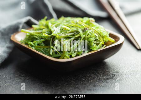 Wakame verde. Insalata di alghe in ciotola di legno. Foto Stock