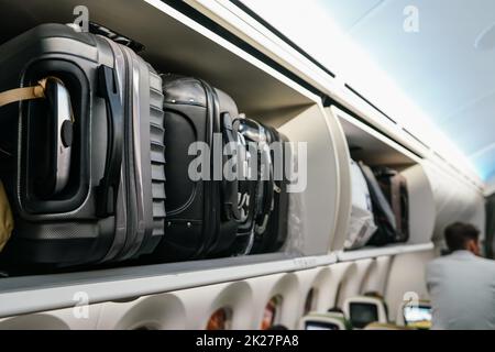 Armadietto aereo con valigie in plastica nera, dettaglio primo piano Foto Stock