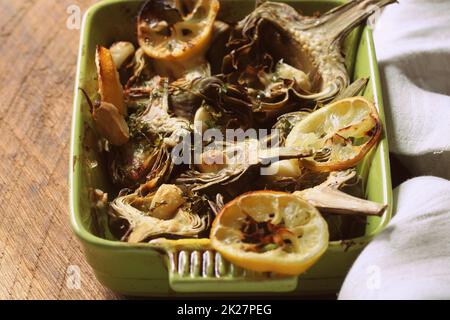 Carciofi fritti con aglio e limone sulla coppa sul tavolo rustico Foto Stock