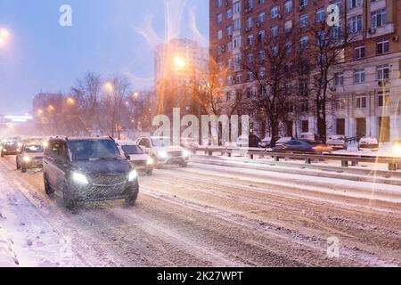 in caso di nevicate, le auto percorrono una strada innevata scivolosa Foto Stock