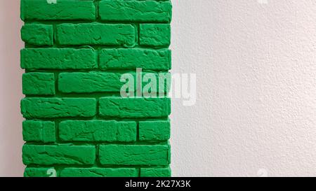 Moderna parete rosa piatta con una colonna decorativa in mattoni dipinta di verde. Astratto moderno sfondo texture trendy. Copia spazio vuoto per il testo e la pubblicità. Foto Stock