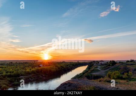 La luce celeste del sole sopra il fiume e la foresta. Cielo serale drammatico con le nuvole e i raggi del sole. Ora d'oro al tramonto serale o alba mattutina. Vista panoramica delle nuvole di cirrus Foto Stock