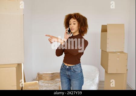 Giovane donna che parla di telefono tra scatole di cartone Foto Stock