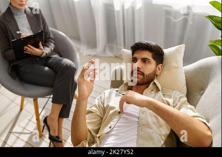 Psicologa femminile che lavora con l'uomo sul divano Foto Stock