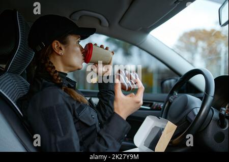 Ufficiale di polizia femminile che ha pranzo durante la giornata lavorativa Foto Stock