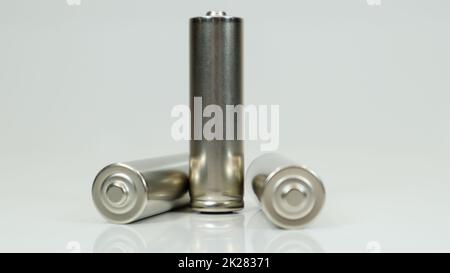 Batterie alcaline AA ricaricabili su sfondo bianco lucido con riflesso. Chiudere tre batterie scariche con spazio per la copia. Foto Stock