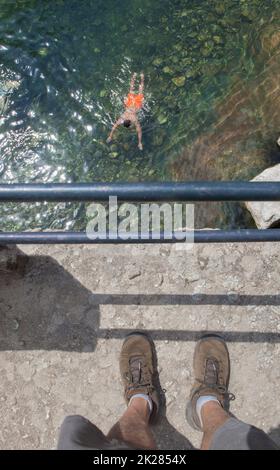 Trekker osservare nuotatore dal parapetto ponte. La Maquina piscina naturale, acque cristalline nel cuore della contea di la vera, Caceres, Estremadura Foto Stock