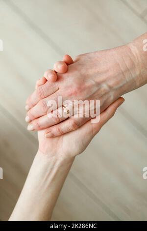 La mano della giovane ragazza tiene la mano della madre anziana. Supporto di vecchia generazione Foto Stock