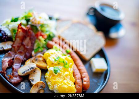 Colazione con uova strapazzate, pancetta, salsicce e pane tostato Foto Stock