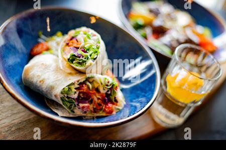 Una ciotola con due pezzi di tortilla vegetariana Foto Stock