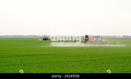 Trattore con dispositivo di spruzzatura per fertilizzante finemente disperso. Foto Stock